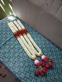 a bunch of beads sitting on top of a blue cloth covered table next to flowers