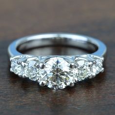 a three stone diamond ring sitting on top of a wooden table