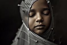 a woman with her eyes closed wearing a silver headdress