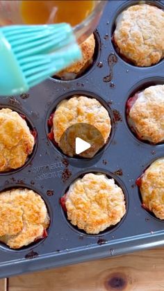 an image of muffins in the pan being cooked with a blue spatula