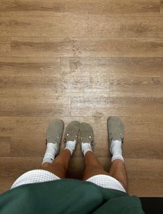 a person standing on top of a wooden floor with their feet up in the air