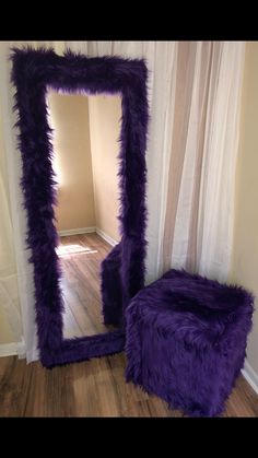 a purple furry stool sitting in front of a mirror on top of a hard wood floor