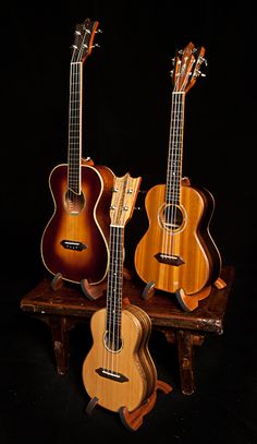 three guitars sitting on top of a wooden stand