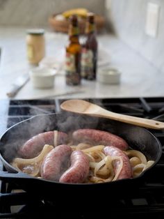 sausages and onions cooking in a skillet on the stove