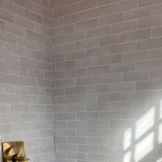 a white toilet sitting next to a bath tub in a bathroom under a brick wall