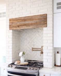 a stove top oven sitting inside of a kitchen next to a white brick wall and counter