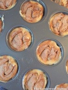 muffins with powdered sugar on top in a baking pan ready to go into the oven