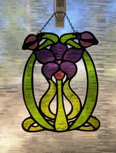 a stained glass window with a flower hanging from it's center and chain attached to the side