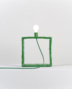 a green lamp sitting on top of a white table next to a lightbulb