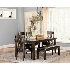 a dinning room table with chairs and a bench in front of the dining room window