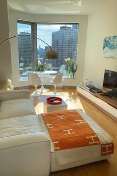 a living room with white furniture and large windows overlooking the cityscape in the background