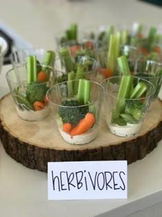 small cups filled with veggies on top of a wooden tray next to a sign that says herb vores