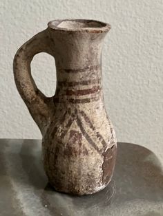 an old vase sitting on top of a table next to a white wall and floor