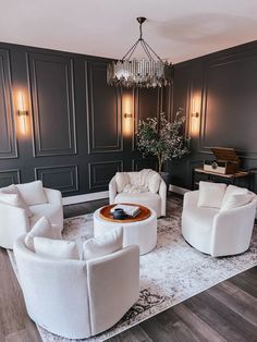 a living room filled with white furniture and a chandelier hanging from the ceiling