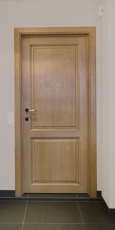 an empty room with a wooden door and tile flooring in front of the door