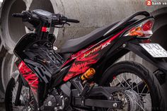 a red and black motorcycle parked in front of some pipes