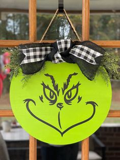 a green door hanger with a black and white checkered bow on it's head