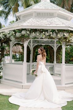 a woman in a wedding dress standing under a gazebo