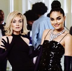 two women standing next to each other in black dresses