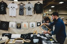 a man and woman looking at t - shirts on display