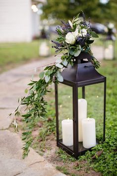 a lantern with candles and flowers on the ground