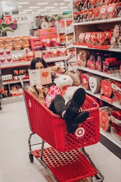 a woman is sitting in a shopping cart with her stuffed animal on the back and she is holding a sign that says i love valentine's day