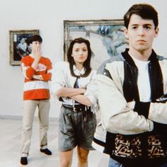 three people standing in an art gallery with their arms crossed