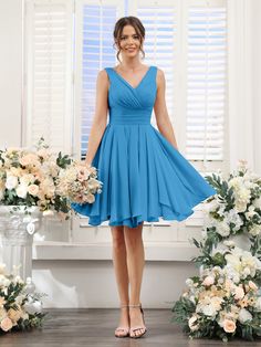 a woman standing in front of flowers wearing a blue bridesmaid dress and heels