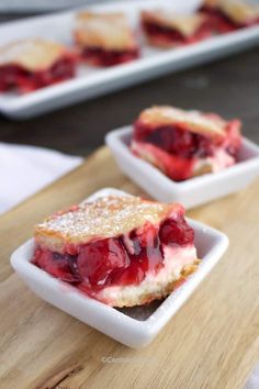 strawberry shortcakes with powdered sugar on top in small white dishes sitting on a wooden cutting board