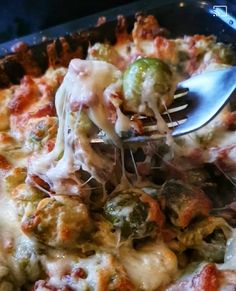 a close up of a fork in a casserole dish with broccoli and cheese