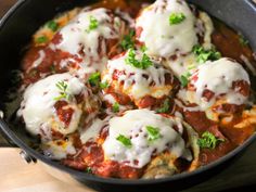 a skillet filled with meatballs covered in sauce and cheese