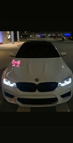 a white car with a pink bow on it's hood parked in a parking lot