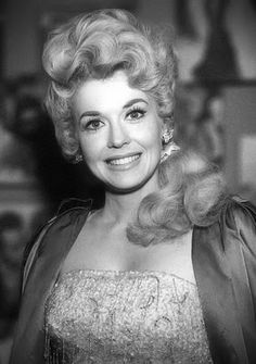 an old black and white photo of a woman in a dress smiling at the camera