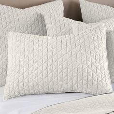 three white pillows sitting on top of a bed