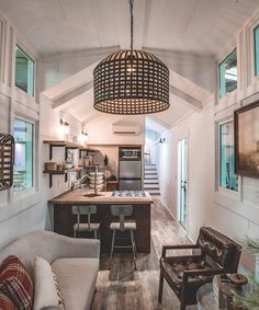 a living room and kitchen area in a small space with wood flooring, white walls and ceiling