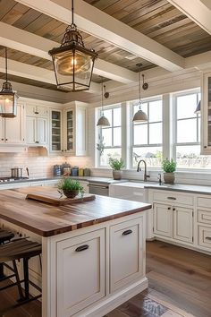 a large kitchen with white cabinets and wooden counter tops, along with an island in the middle