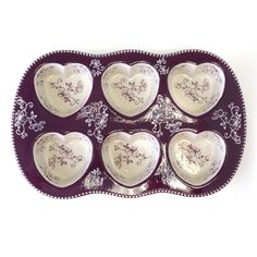 six heart shaped dishes in a tray on a white surface with purple trimmings