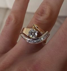 a woman's hand with a gold and white diamond ring on top of her finger