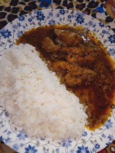 a plate with rice, meat and gravy on it sitting on a table