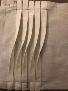 four pieces of white linen with black stitching on them, lined up against each other