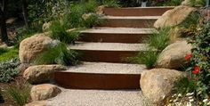 the steps are made out of stone and have plants growing on each side, along with flowers