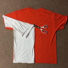 an orange and white t - shirt with scissors laying on the floor next to it