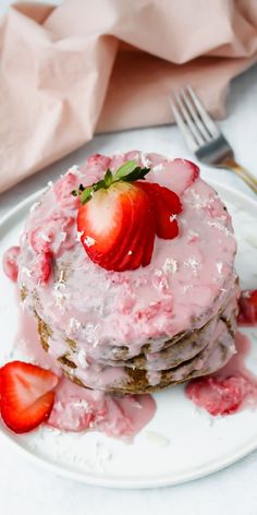 a stack of pancakes covered in frosting and strawberries on top of a white plate