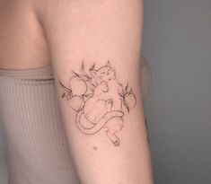 a woman's arm with a small tattoo of a cat and flowers on it