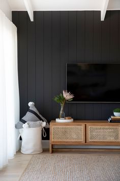 a living room with black walls and wicker furniture, including a large flat screen tv