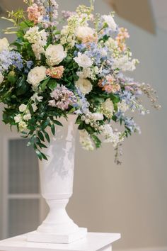 a white vase filled with lots of different colored flowers