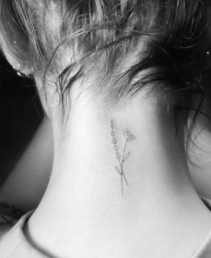 a woman's back neck with a small flower tattoo on the left side of her neck