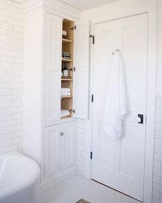 a bathroom with white walls and flooring next to a bathtub filled with towels