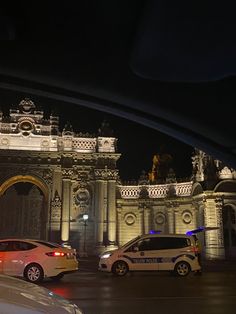 two police cars are parked in front of an ornate building at night with lights on