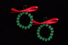 two christmas wreaths with red ribbon and green beaded beads on a black background